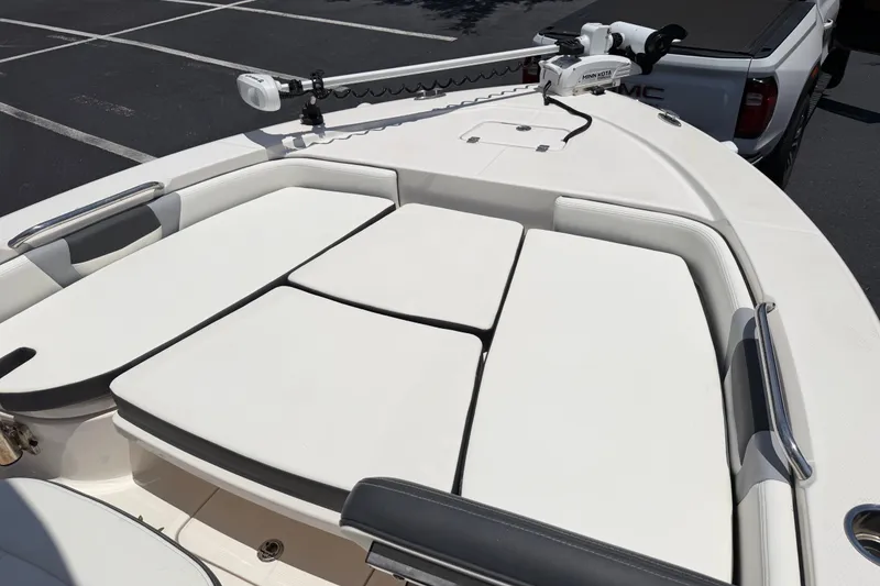 Slide: The Image of 2023 Robalo 226 Cayman boat with cushioned bow seating and trolling motor in parking lot. - 7