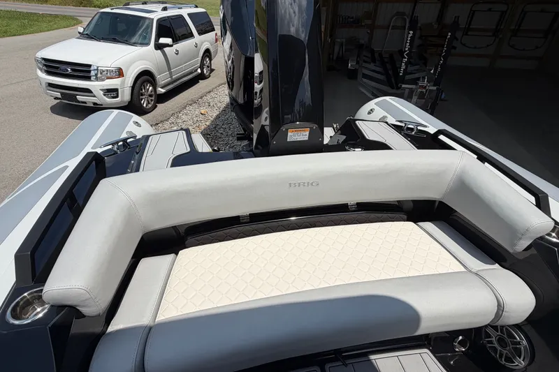 Slide: The Image of 2027 Brig Eagle 8 boat interior with white seating, parked near a white SUV. - 25