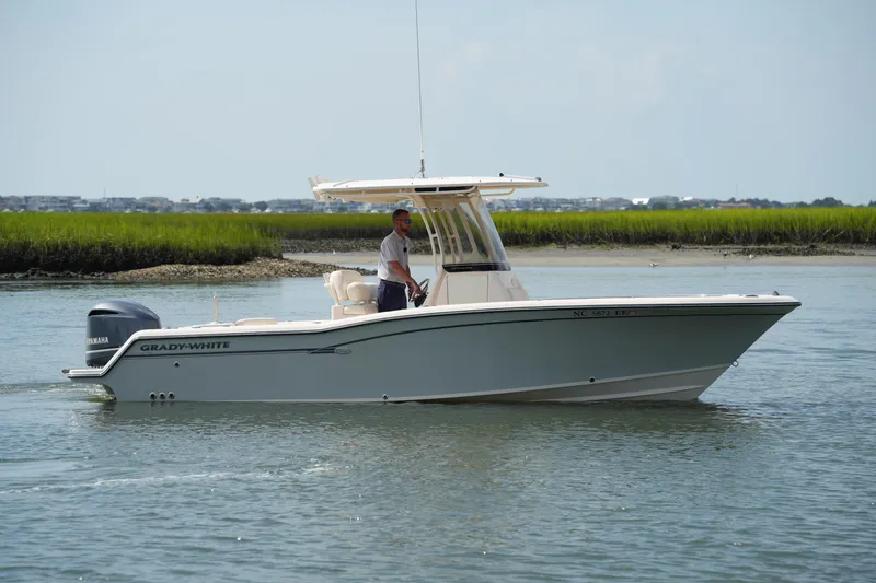 The Image of 2017 Grady-White Fisherman 236 boat cruising on calm water near grassy shoreline. - 0
