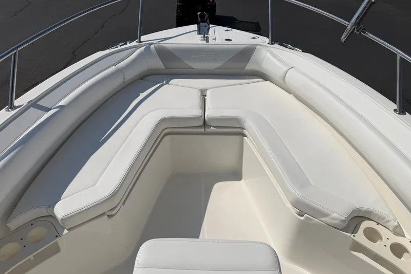 Slide: The Image of 2014 Boston Whaler 220 Outrage boat with white cushioned seating and stainless steel railings. - 5