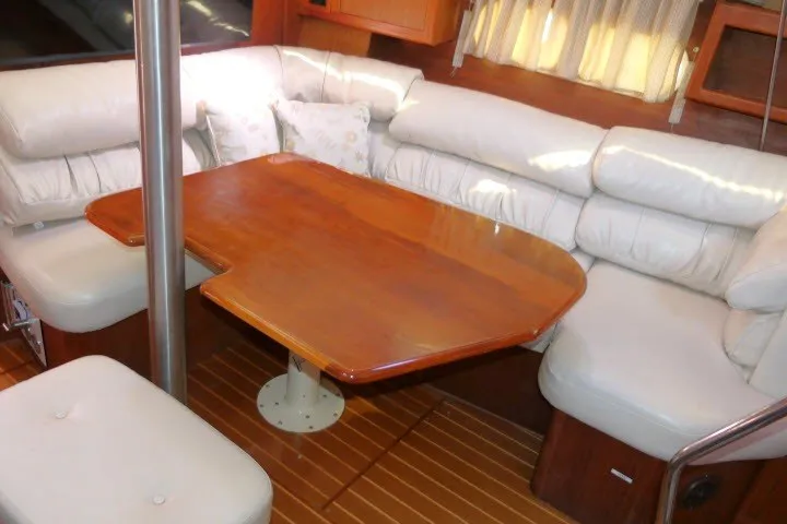 Slide: The Image of Interior of a 2001 Hunter 420 sailboat with a wooden dining table and white cushioned seating. - 11