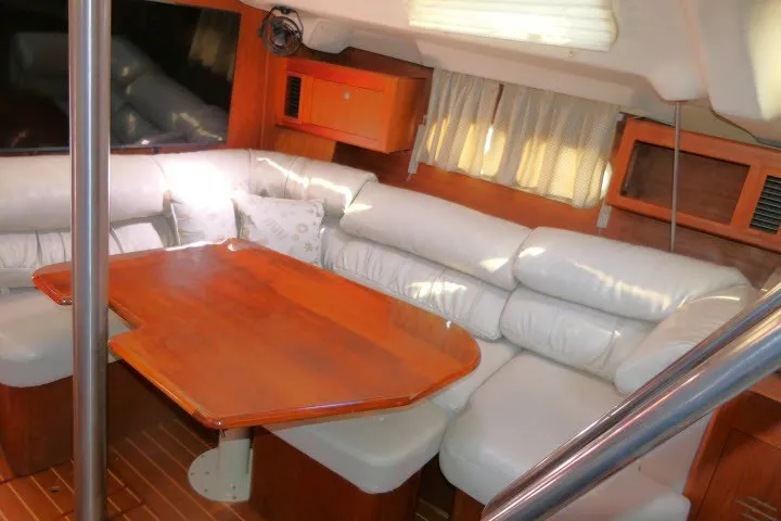 Slide: The Image of Interior of a 2001 Hunter 420 yacht with white leather seating and wooden table. - 9