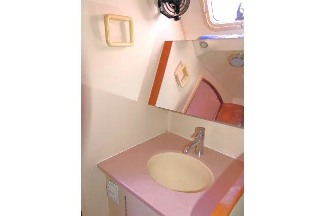 Slide: The Image of Bathroom sink area in a 2001 Hunter 420 sailboat, featuring a mirror and faucet. - 34