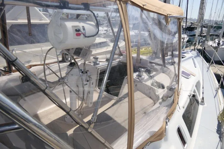 Slide: The Image of 2001 Hunter 420 sailboat cockpit with clear enclosure and steering wheel in marina. - 48