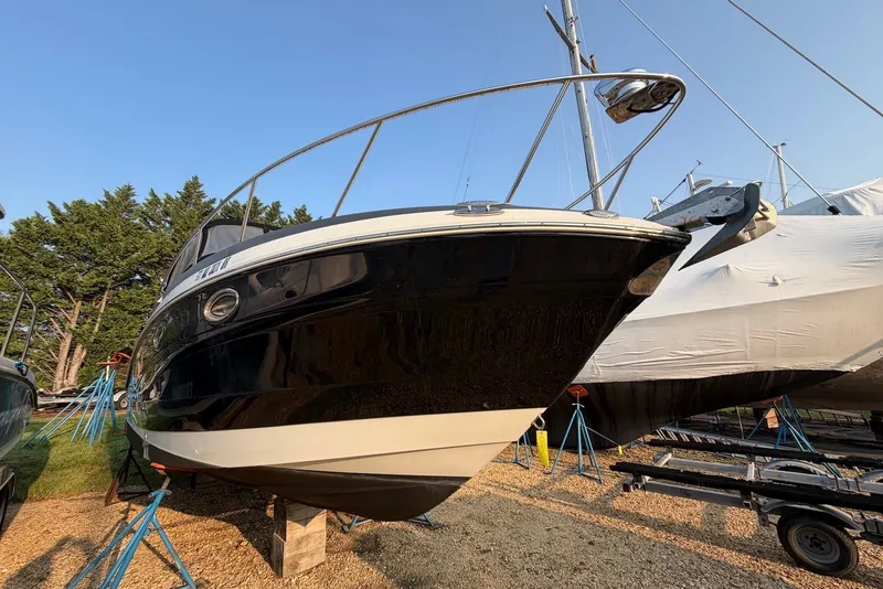 Slide: The Image of 2020 Crownline 264 CR boat on stands, outdoor storage, clear sky background. - 3