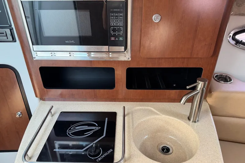 Slide: The Image of 2020 Crownline 264 CR boat kitchen with microwave, sink, and stovetop. - 20
