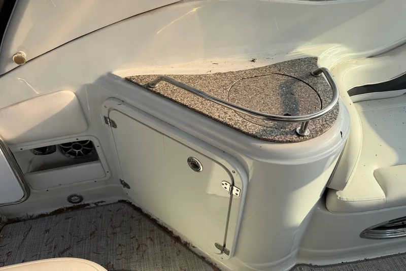 Slide: The Image of Interior of 2020 Crownline 264 CR boat featuring a compact kitchenette with granite countertop. - 13