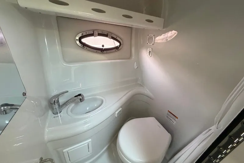 Slide: The Image of Compact bathroom in 2020 Crownline 264 CR boat with sink, toilet, and porthole window. - 23