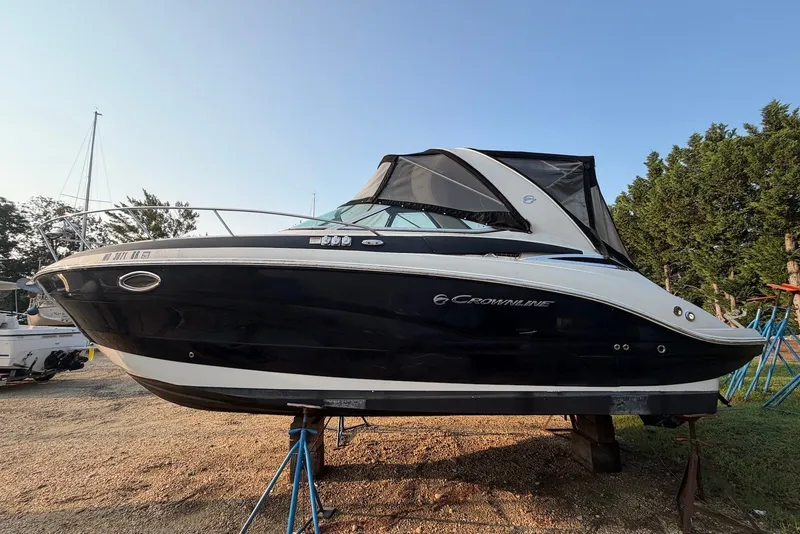 The Image of 2020 Crownline 264 CR boat on stands, black and white exterior, parked outdoors. - 0