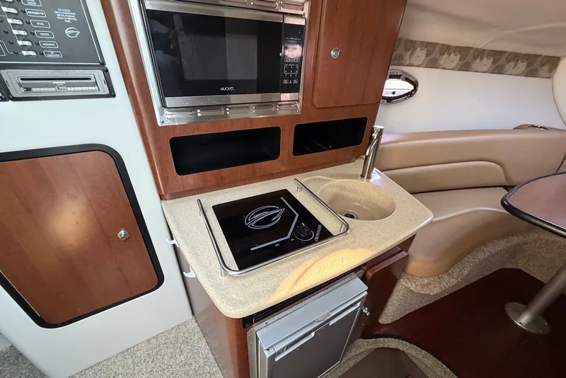 Slide: The Image of 2020 Crownline 264 CR boat interior with kitchenette, microwave, and seating area. - 18