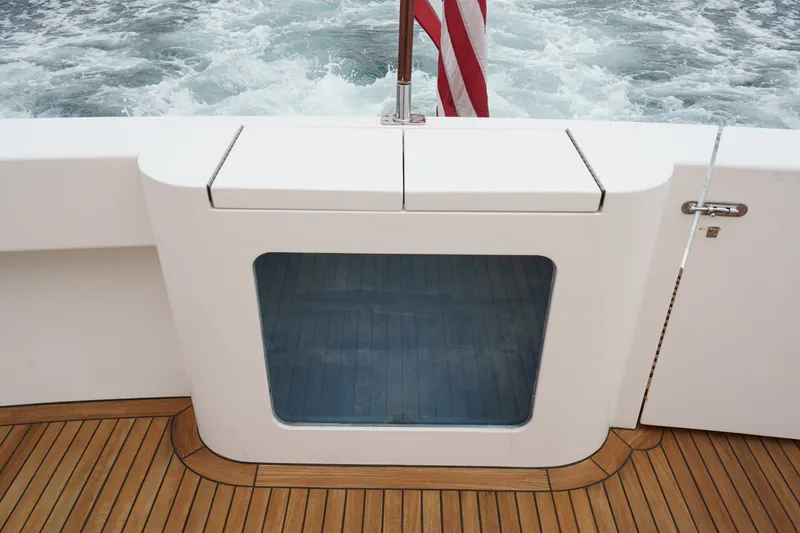Slide: The Image of The image shows the stern of a 2005 West Bay 80 CPMY with teak decking and a flag. - 31