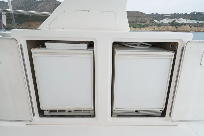 Slide: The Image of Two white refrigerators are built into a boat, with a coastal landscape in the background. - 25