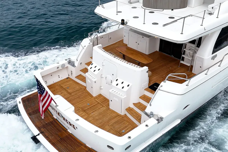 Slide: The Image of The 2005 West Bay 80 CPMY features an elegant aft deck with teak flooring and an American flag. - 28