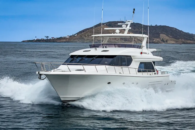 Slide: The Image of The 2005 West Bay 80 CPMY cruises swiftly through the water near a rocky coastline. - 7