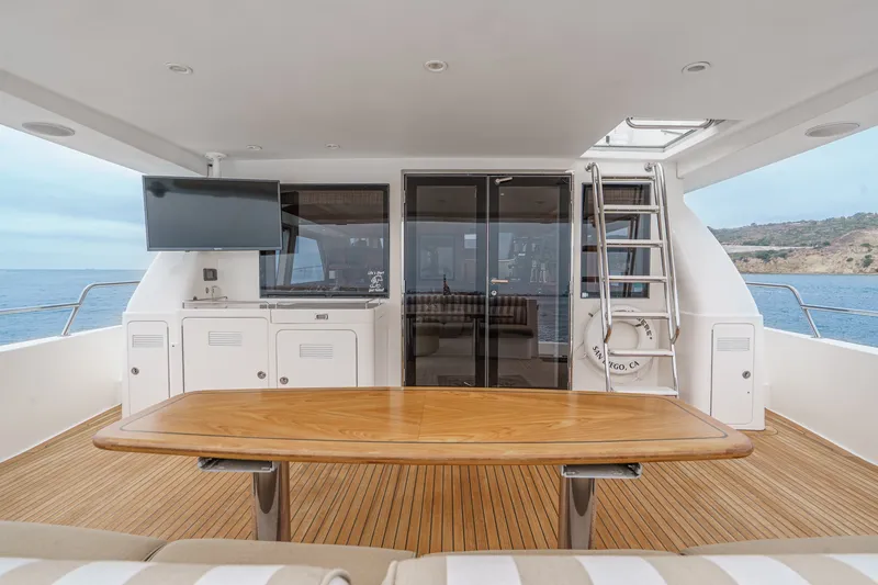 Slide: The Image of The 2005 West Bay 80 CPMY features an elegant aft deck with a wooden table and ocean view. - 39