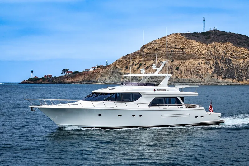 The Image of A luxurious white yacht cruises near a rocky coastline with a lighthouse in the background. - 0