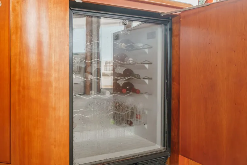 Slide: The Image of A wine cooler with a glass door, filled with wine bottles, built into a wooden cabinet. - 46