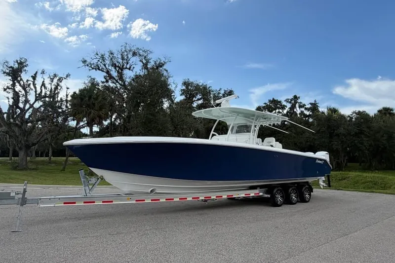 Slide: The Image of 2012 Bahama 37 boat on trailer, parked on road with trees in background. - 1