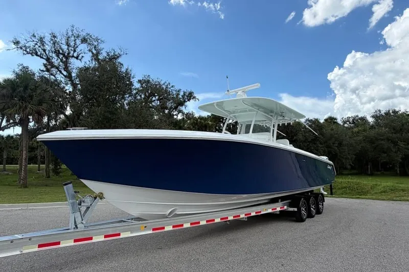 Slide: The Image of 2012 Bahama 37 boat on trailer, parked outdoors under a clear blue sky. - 2