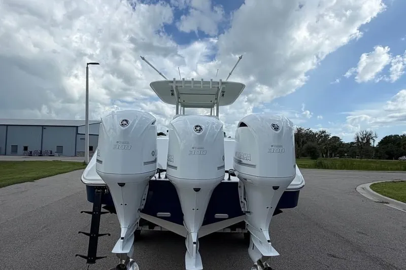 Slide: The Image of 2012 Bahama 37 boat with triple Yamaha 300 engines, parked outdoors under a cloudy sky. - 9