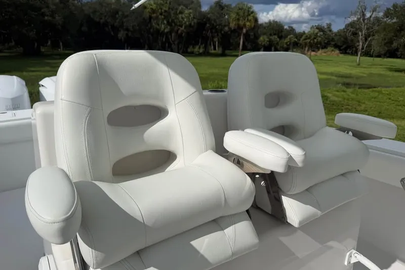 Slide: The Image of Luxurious white seating on a 2012 Bahama 37 boat, set against a lush green backdrop. - 16