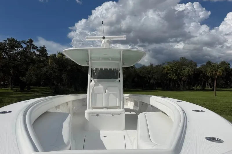Slide: The Image of 2012 Bahama 37 boat with sleek white design, set against a cloudy sky and lush greenery. - 13