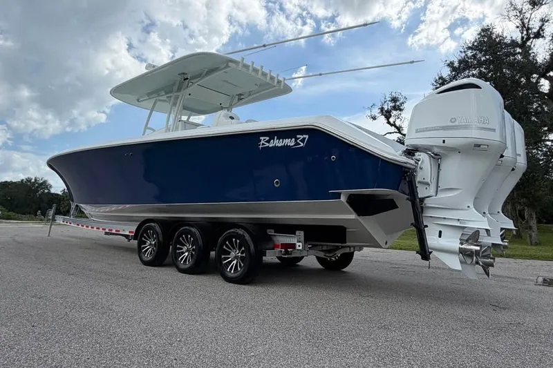 Slide: The Image of 2012 Bahama 37 boat on trailer with triple Yamaha engines, under a cloudy sky. - 8