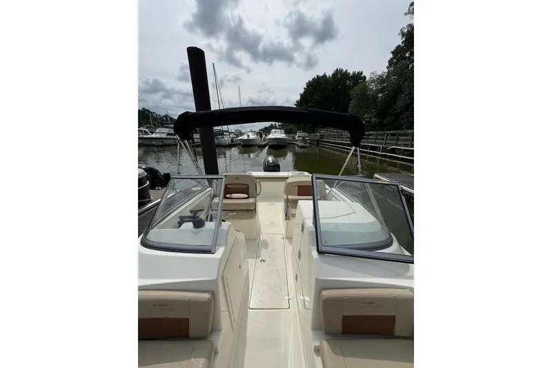 Slide: The Image of 2024 Cobia 220 Dual Console boat docked at marina, featuring sleek design and spacious seating. - 5
