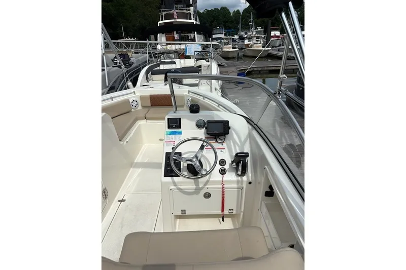 Slide: The Image of 2024 Cobia 220 Dual Console boat interior with steering wheel and control panel. - 8