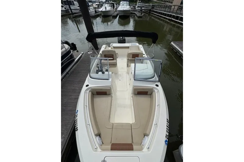 Slide: The Image of 2024 Cobia 220 Dual Console boat docked in a marina, showcasing spacious seating. - 1