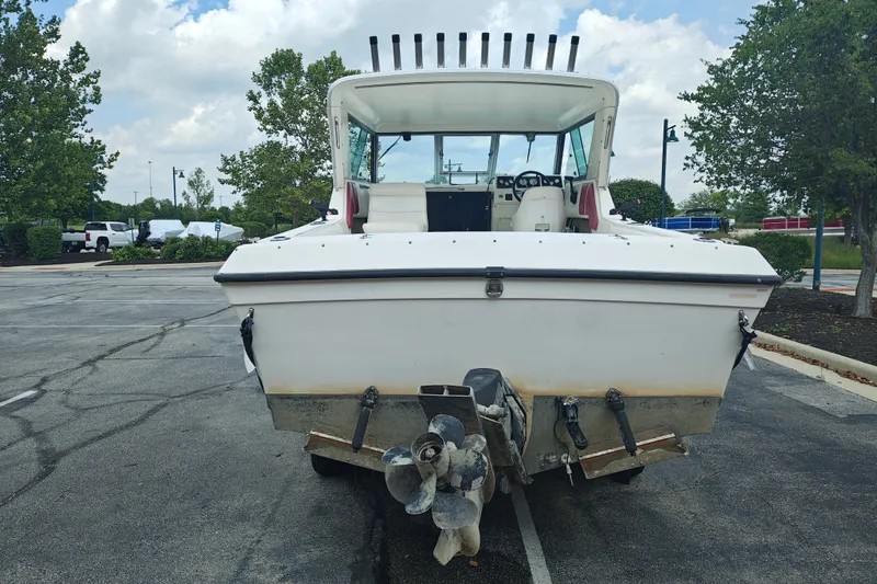 Slide: The Image of 1996 SportsCraft 232HT boat parked in a lot, rear view with trees and cloudy sky. - 7