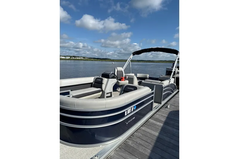 The Image of 2024 Harris Cruiser 230 pontoon boat docked on a sunny day by the water. - 1