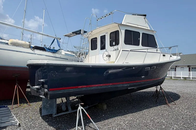 Slide: The Image of 1999 Judge Eastern 31 Flybridge boat on dry dock, blue hull, white cabin, clear sky. - 1