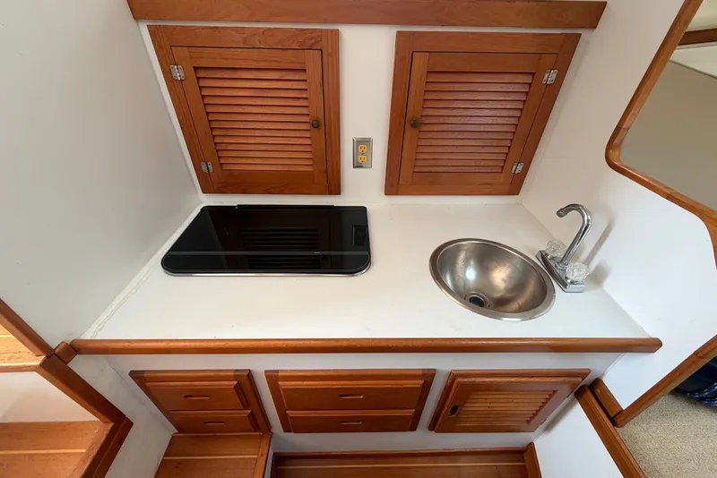 Slide: The Image of Compact galley in 1999 Judge Eastern 31 Flybridge with sink, stove, and wooden cabinets. - 11