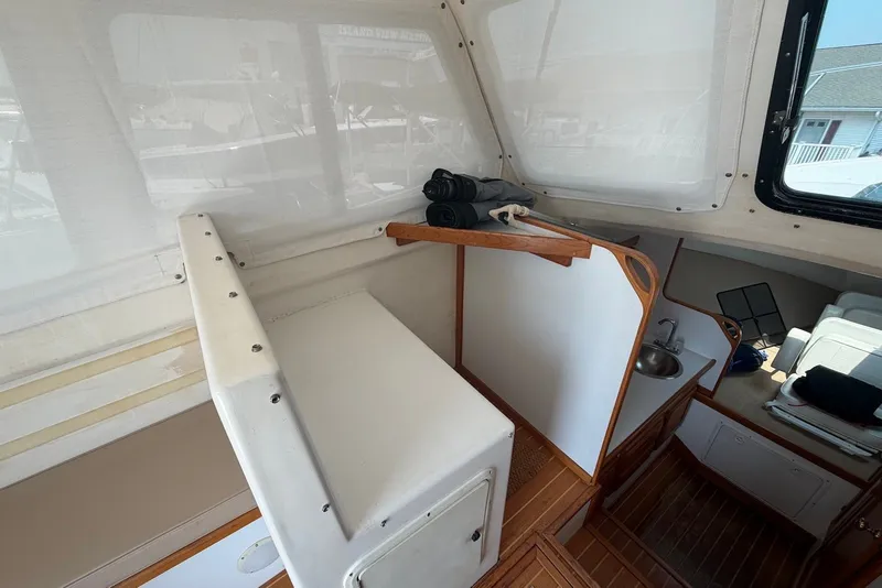 Slide: The Image of 1999 Judge Eastern 31 Flybridge interior with seating, sink, and wooden accents. - 9