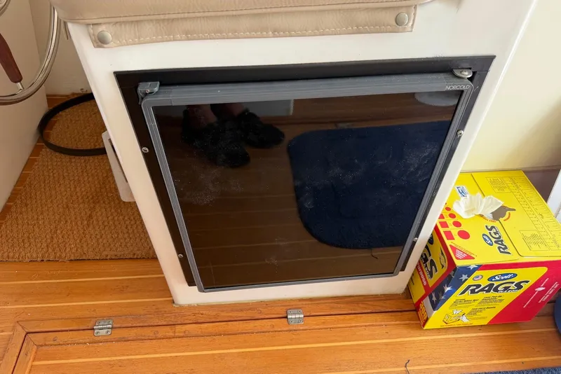 Slide: The Image of Interior of a 1999 Judge Eastern 31 Flybridge with a Norcold fridge and cleaning rags. - 13