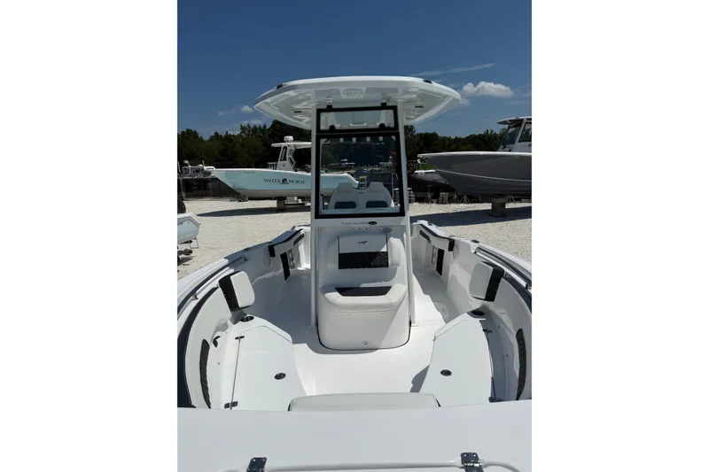 Slide: The Image of 2027 Tidewater 220 CC Adventure boat interior with seating and console under clear sky. - 2