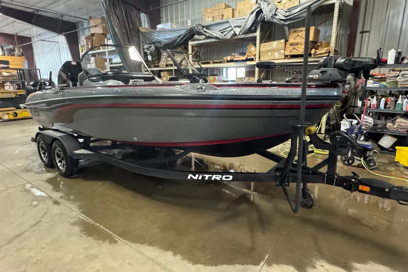 Slide: The Image of 2019 Nitro ZV19 boat in a warehouse, on a trailer, surrounded by shelves and equipment. - 2
