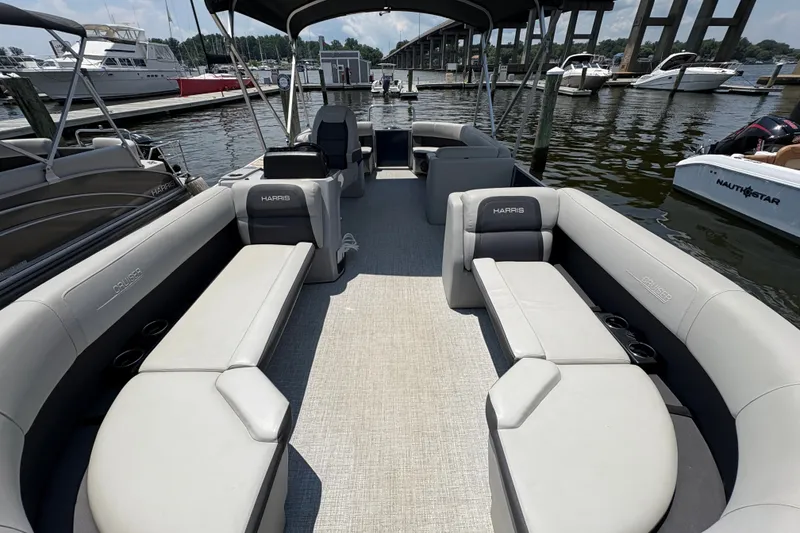 Slide: The Image of 2024 Harris Cruiser 230 pontoon boat interior with spacious seating at a marina. - 5