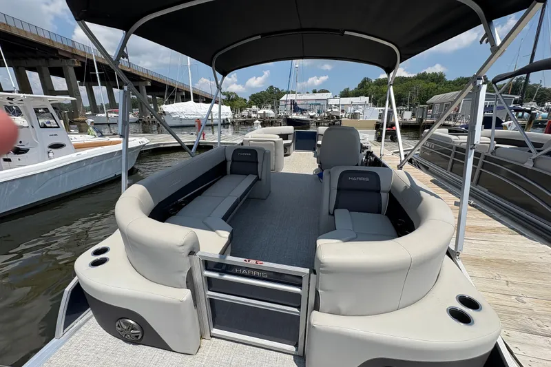 Slide: The Image of 2024 Harris Cruiser 230 pontoon boat docked at a marina under a sunny sky. - 6