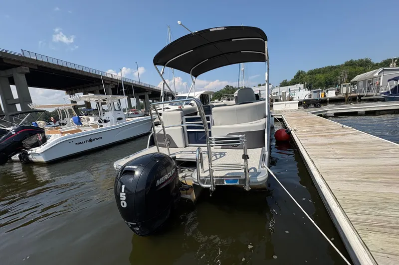 Slide: The Image of 2024 Harris Cruiser 230 pontoon boat docked with Mercury outboard motor. - 4