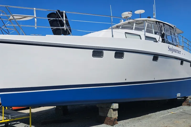Slide: The Image of 2005 Endeavour 44 TrawlerCat boat on dry dock, white and blue hull, named "Sojourner". - 84