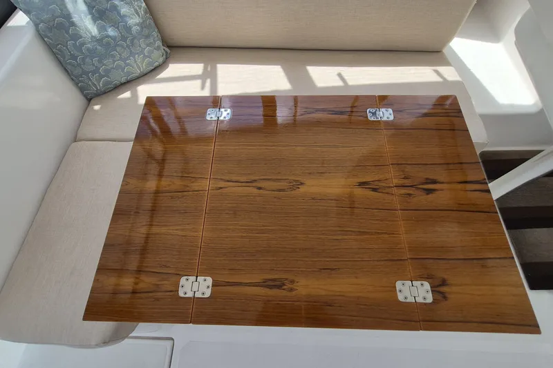 Slide: The Image of Wooden table with hinges on a 2005 Endeavour 44 TrawlerCat, beige seating, and decorative pillow. - 4