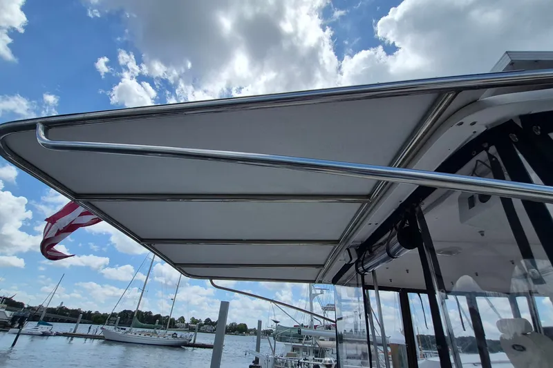 Slide: The Image of 2005 Endeavour 44 TrawlerCat boat canopy with American flag, docked under blue sky. - 19