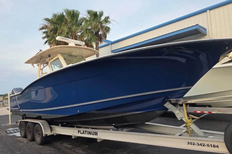 Slide: The Image of 2017 Scout 350 LXF boat on trailer, blue hull, parked near palm trees. - 48