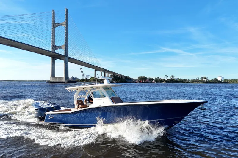Slide: The Image of 2017 Scout 350 LXF boat cruising under a bridge on a sunny day. - 19