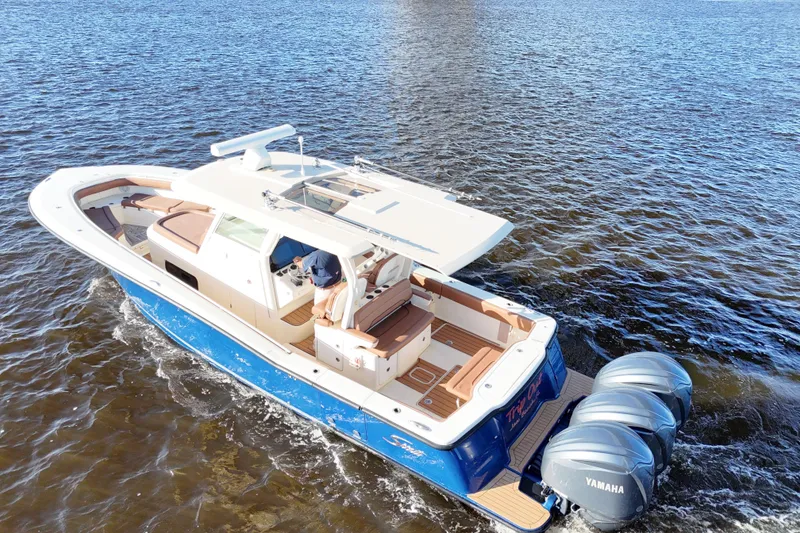 Slide: The Image of 2017 Scout 350 LXF boat cruising on water with triple Yamaha engines. - 15
