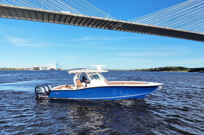 Slide: The Image of 2017 Scout 350 LXF boat cruising under a bridge on a sunny day. - 2