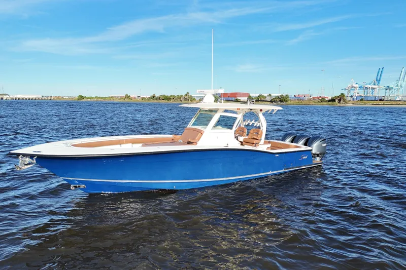 Slide: The Image of 2017 Scout 350 LXF boat on water, blue hull, clear sky, industrial background. - 6