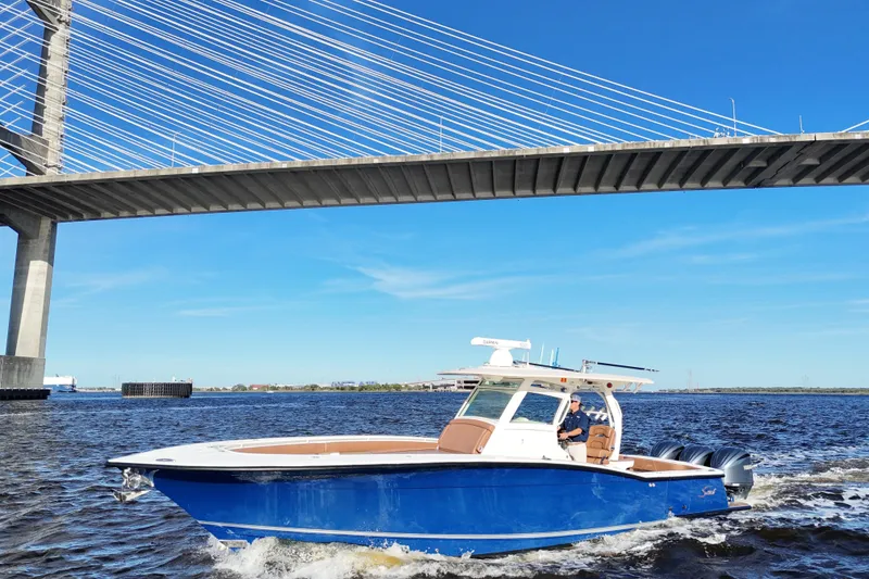 Slide: The Image of 2017 Scout 350 LXF boat cruising under a bridge on a sunny day. - 8